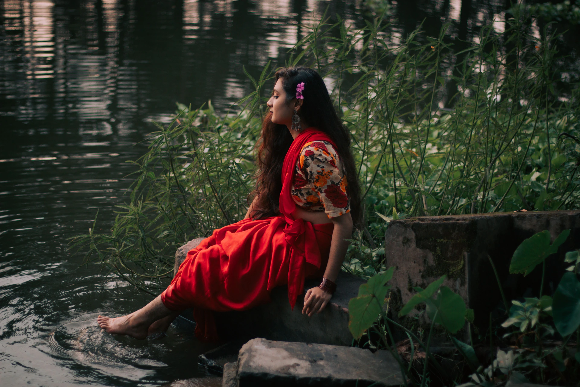 Woman in a red dress sitting beside a calm lake